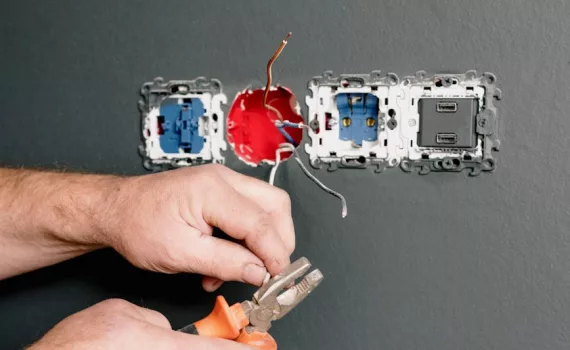 an electrician using pliers to repair the ac power plugs and sockets
